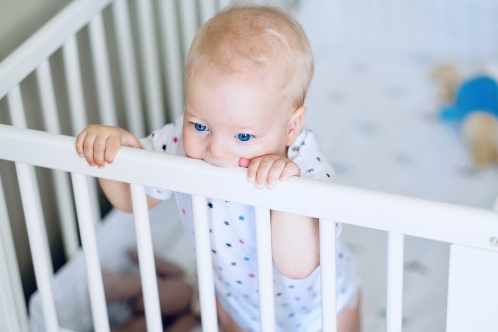 Baby boy with blue eyes standing in crib
