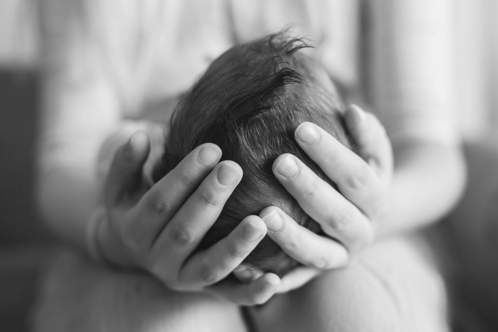 Mother holding babies head in both hands, black and white image